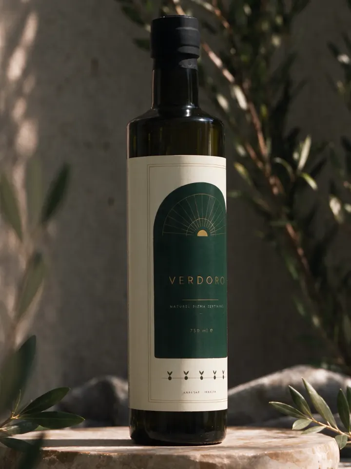 VERDORO 750 mL cam şişe, taş bir sehpanın üzerinde, zeytin dalları arasında